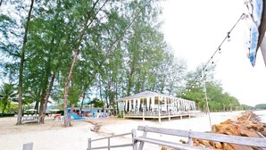A beachside wooden deck with a view of a beach, a covered seating area, and a rocky shoreline. - Suvarn Gleaw Thong Resort (Trat)