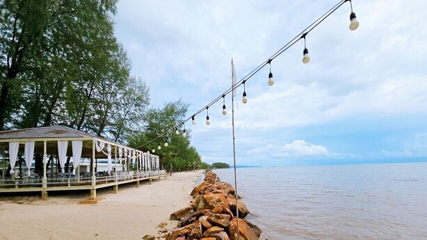 A beachside pier with a row of rocks leading to a covered seating area. - Suvarn Gleaw Thong Resort (Trat)