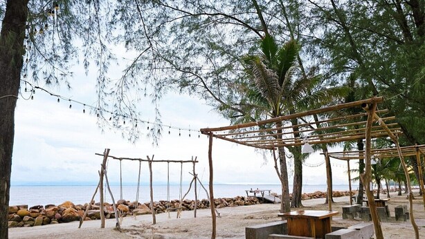 A beach setting with wooden structures, including a swing set and a shaded area with benches. - Suvarn Gleaw Thong Resort (Trat)
