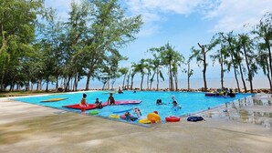 A swimming pool surrounded by trees, with people and inflatable toys. - Suvarn Gleaw Thong Resort (Trat)