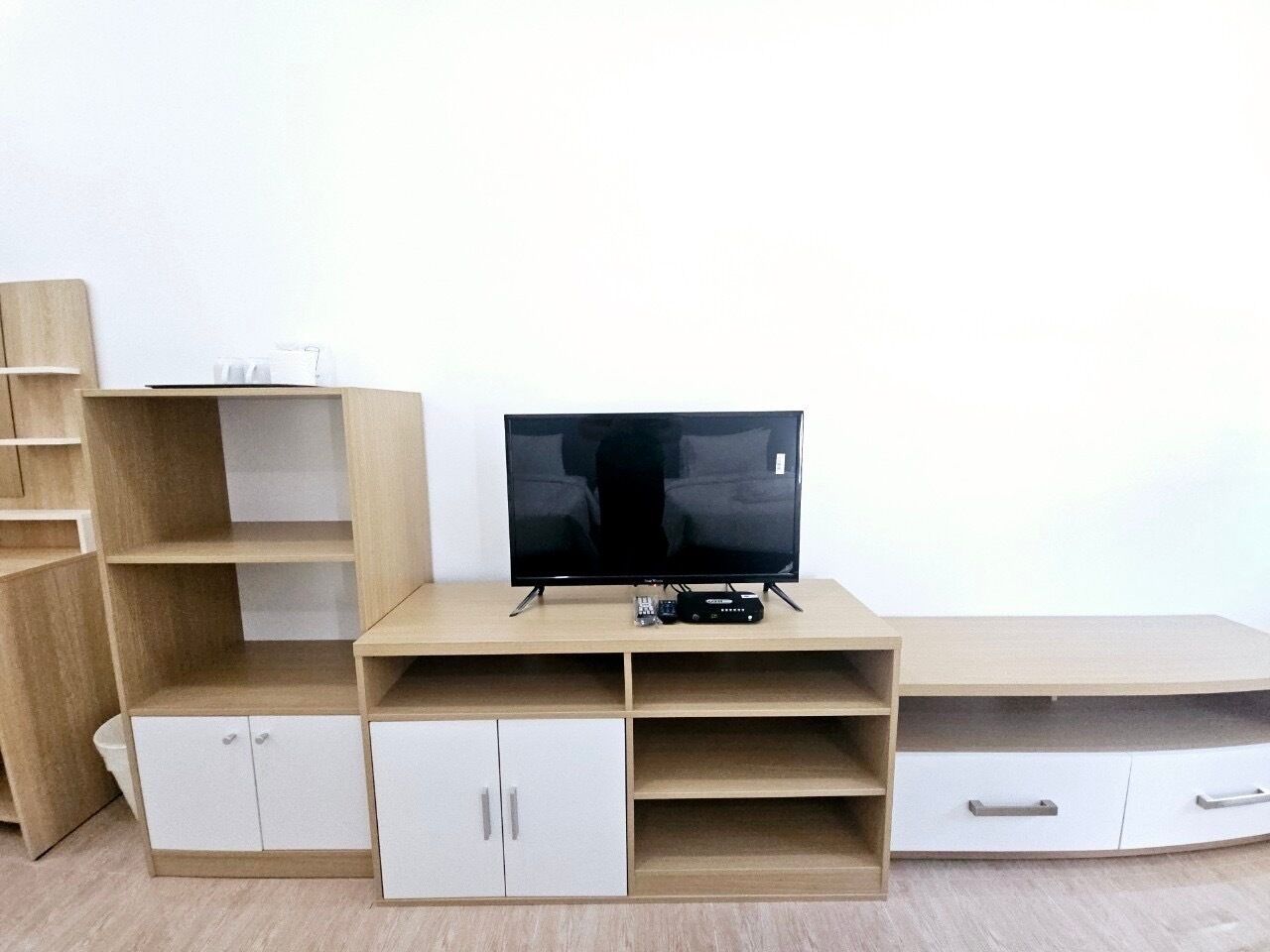 Un mueble moderno de entretenimiento con televisor de pantalla plana, estanterías integradas y armarios de almacenamiento.