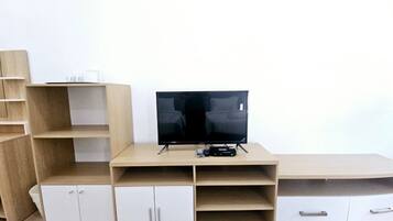 Un mueble moderno de entretenimiento con televisor de pantalla plana, estanterías integradas y armarios de almacenamiento.