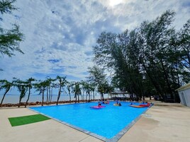 Una piscina con agua cristalina azul, rodeada de árboles y vistas al mar.