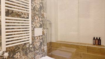 A bathroom with a shower, toilet, and a floral-patterned wall.