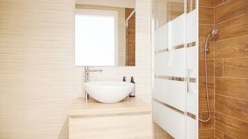 A modern bathroom with a large white sink, a mirror above it, and a shower area with wooden tiles.