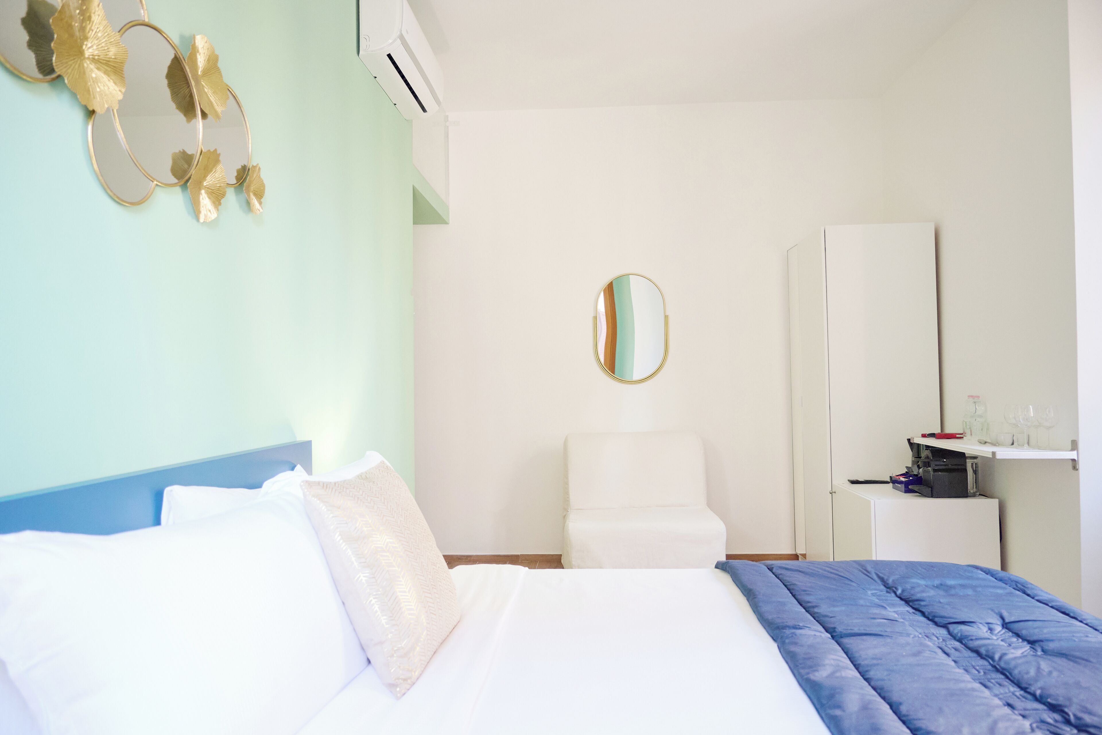 Un dormitorio con una cama, una silla, un armario y un espejo.