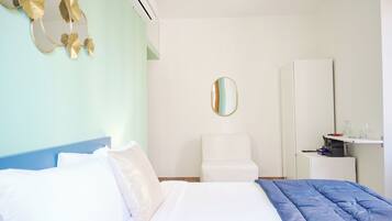Un dormitorio con una cama, una silla, un armario y un espejo.