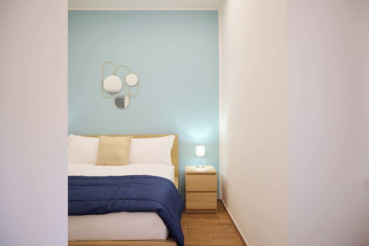 Ein Schlafzimmer mit Bett, Nachttisch und Spiegel an der Wand.