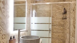 Ein modernes Badezimmer mit einer Glaskabine, einem runden Waschbecken und fliesenmuster.