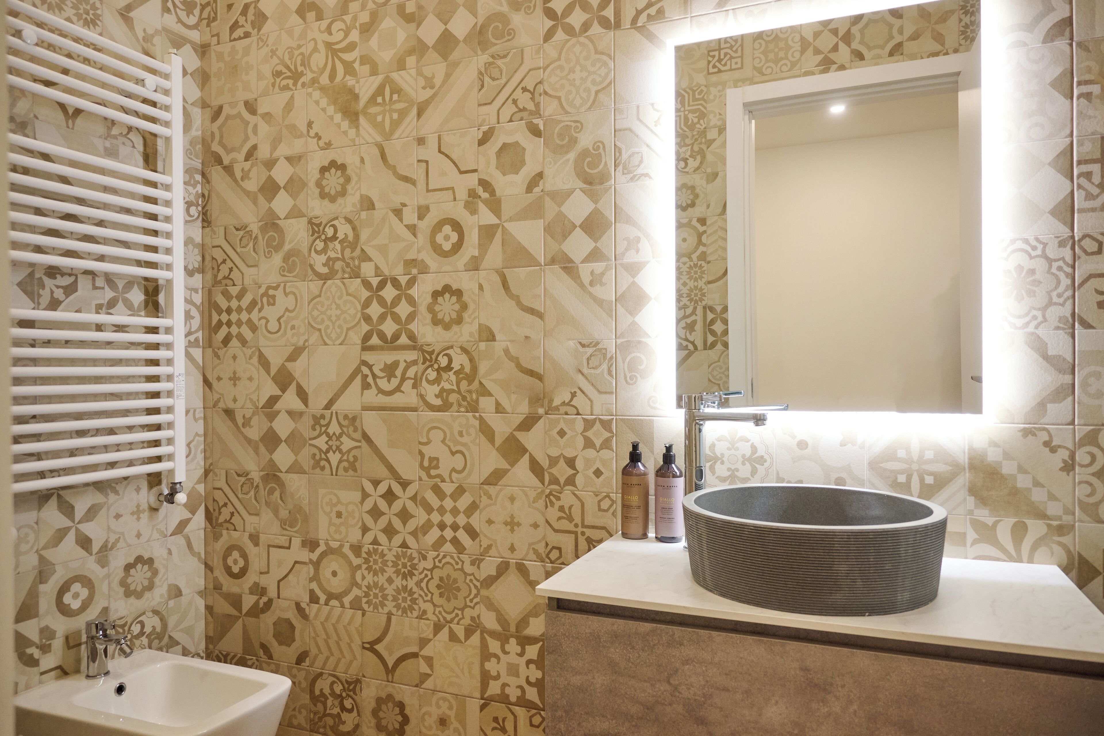 A bathroom with patterned tiles, a white sink, and a mirror.