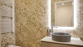 A bathroom with patterned tiles, a white sink, and a mirror.