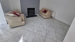 Una sala de estar con dos sofás beige, una chimenea y un radiador.