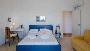 Une chambre d’hôtel avec un lit, un bureau, une chaise, une petite table et un canapé.