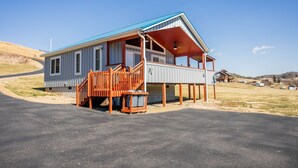 A single-story house with a blue roof and a covered porch. - Charming riverside with stunning views, cozy interiors, full amenities, and spacious decks. (Draper)