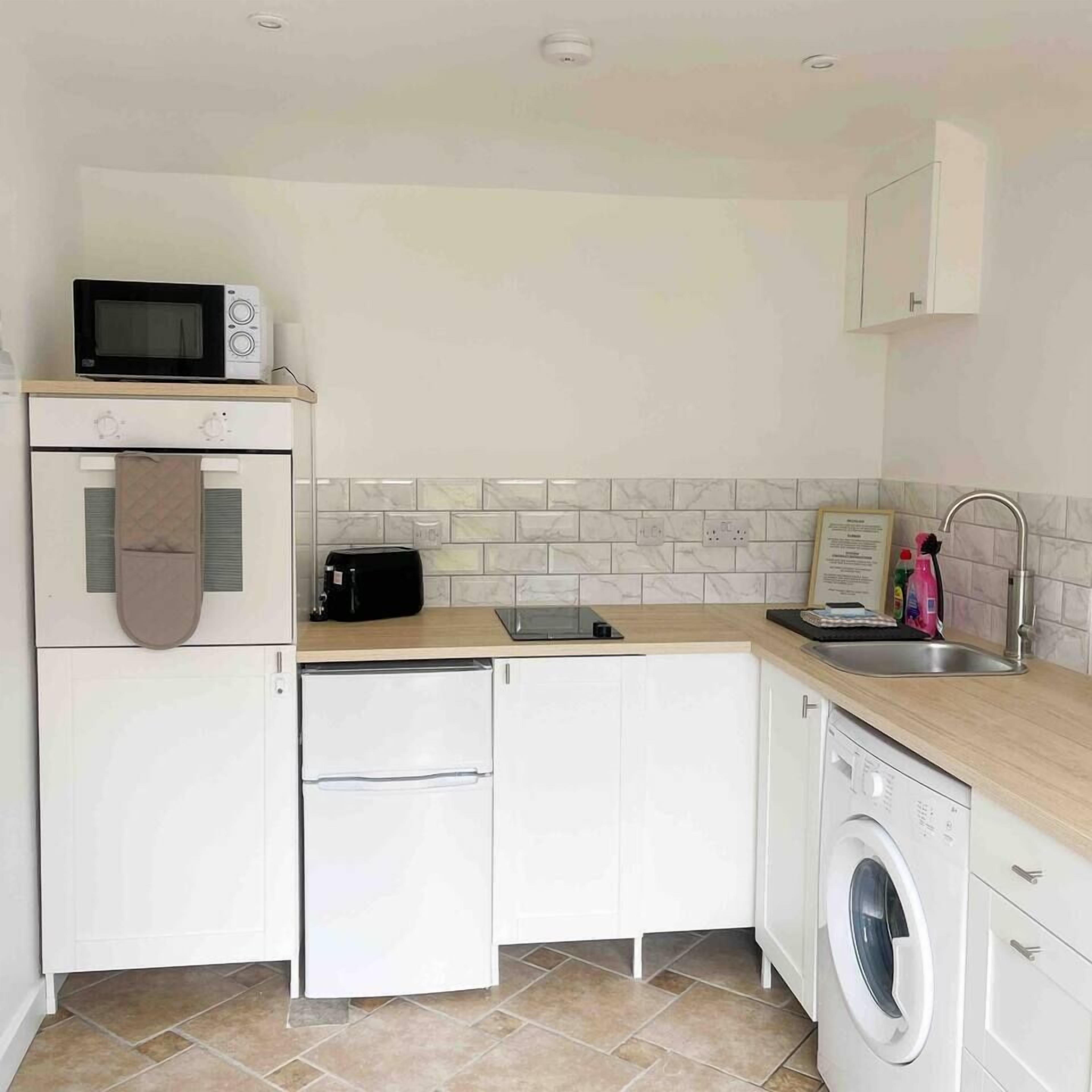 A compact kitchen with a microwave, toaster, and washing machine.