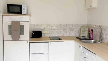 A compact kitchen with a microwave, toaster, and washing machine.