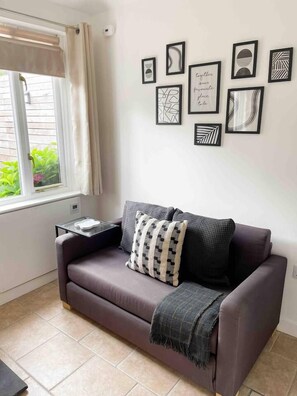 Un salon avec un canapé, une petite table et une fenêtre avec des rideaux.