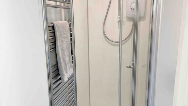 A glass-enclosed shower with a towel rack and a control panel. - Cosy Annex sleeps 2 near Gretna, M6 Jct 45 / A75

 (Rigg)
