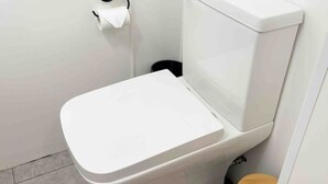 A white toilet with a wooden seat and a black trash bin beside it. - Cosy Annex sleeps 2 near Gretna, M6 Jct 45 / A75

 (Rigg)