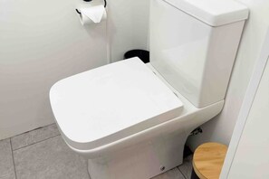 A white toilet with a wooden seat and a black trash bin beside it. - Cosy Annex sleeps 2 near Gretna, M6 Jct 45 / A75

 (Rigg)