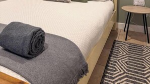 A neatly made bed with a grey blanket and pillows, a small bedside table with a lamp, and a wall-mounted artwork above the bed. - Cosy Annex sleeps 2 near Gretna, M6 Jct 45 / A75

 (Rigg)