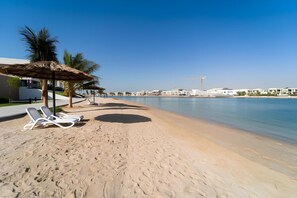 Relax on the beach with comfortable lounge chairs and a shaded umbrella.