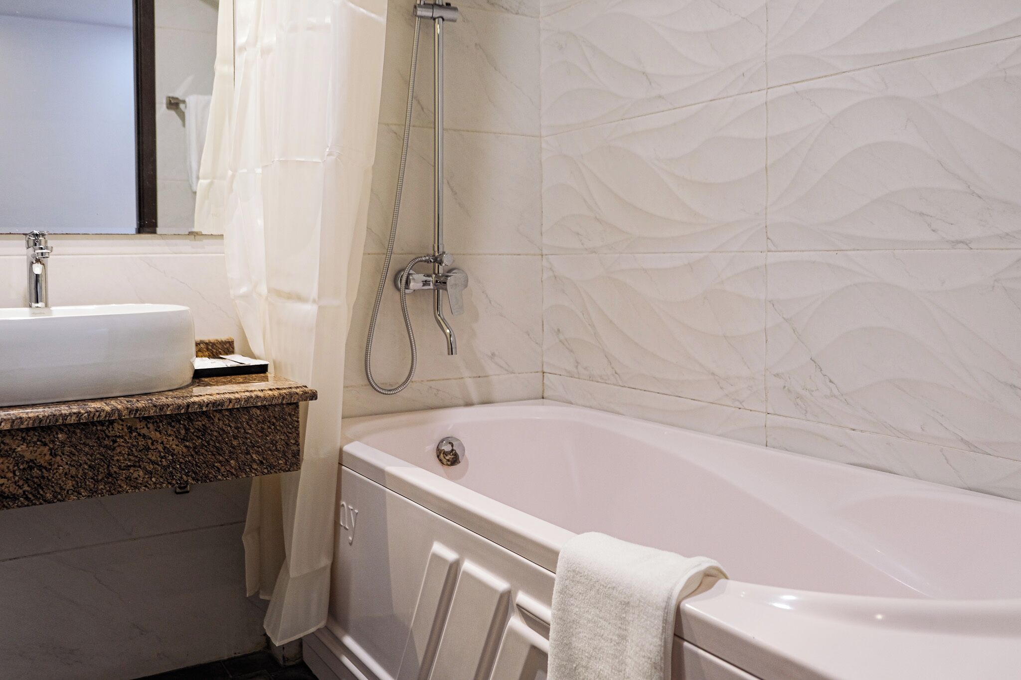 Un baño con una bañera blanca, un lavamanos y una ducha.