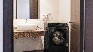 A compact bathroom with a sink, mirror, and a black washing machine. - Hanoi Bliss Apartment Ba Dinh (Hanoi)