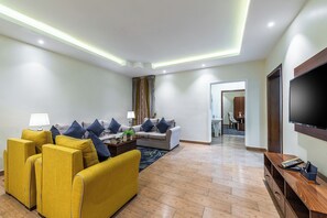 Een moderne woonkamer met een zithoek, een salontafel en een flatscreen televisie.