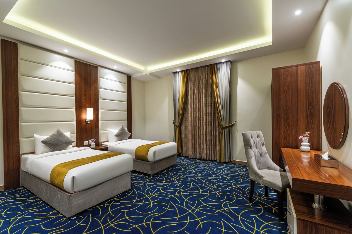 A hotel room with two beds, a desk, and a chair.