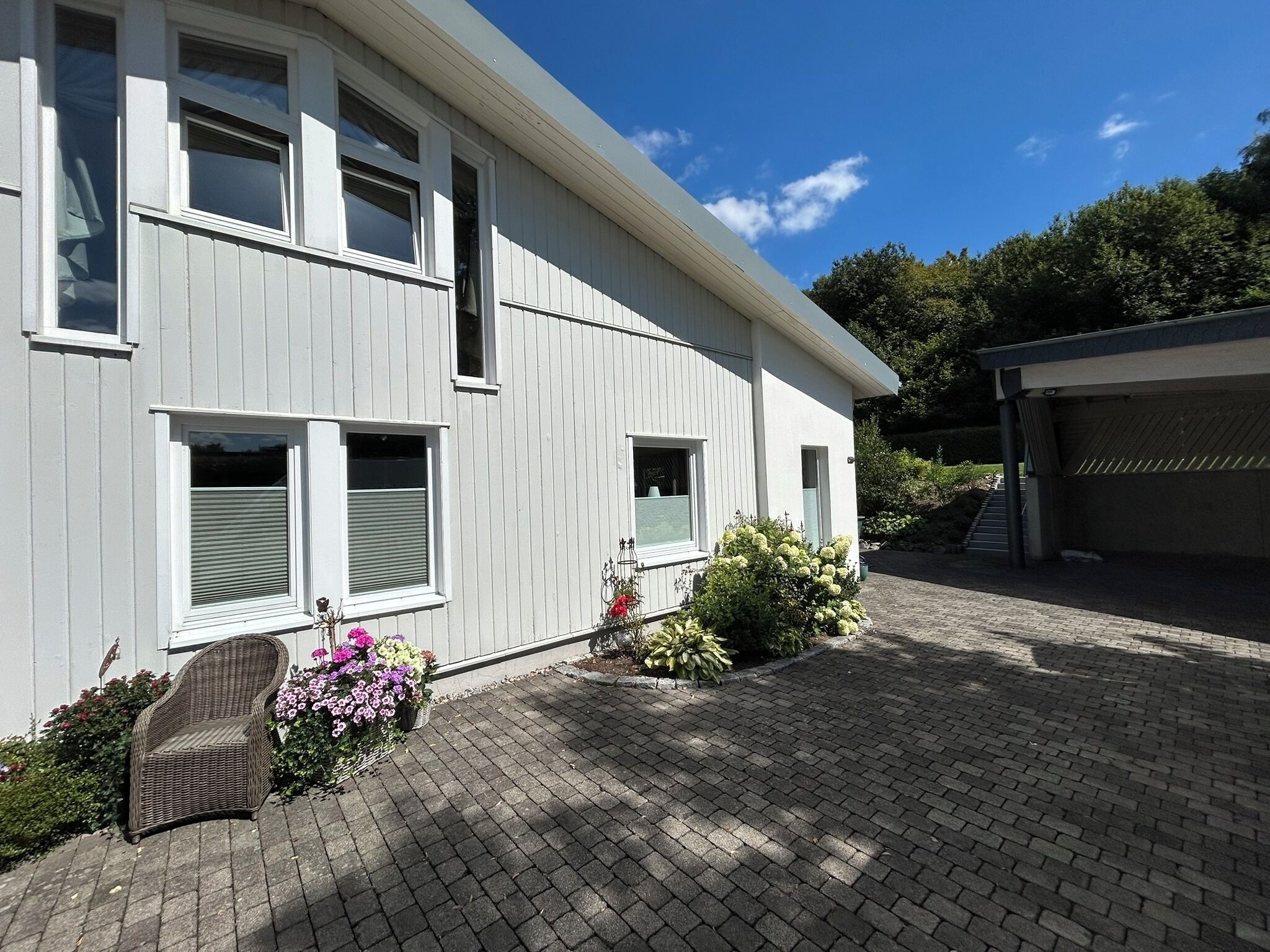 Une maison à deux étages avec une allée pavée et un petit jardin agrémenté de fleurs et d’arbustes.