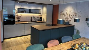 A modern kitchen with a central island, built-in appliances, and pendant lighting. - Workshop chalet ZH10 (Olsberg)