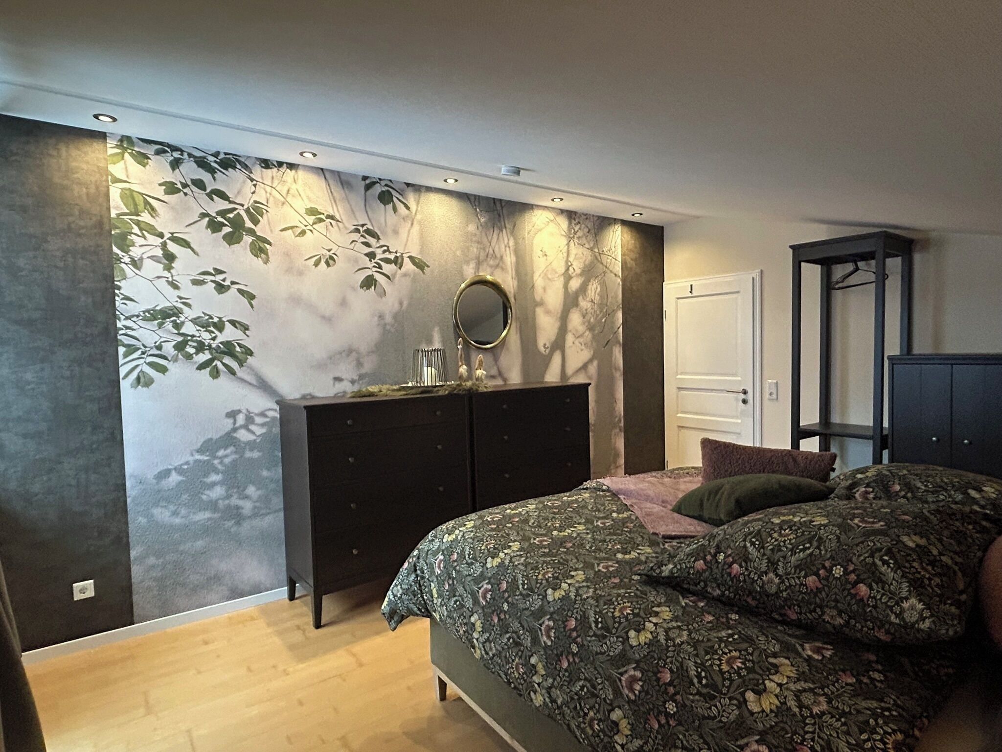 Une chambre à coucher avec un lit, une commode, un miroir et une armoire.
