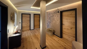 A modern hallway with wooden flooring, a central column, and a decorative wall with leaf patterns. - Workshop chalet ZH10 (Olsberg)