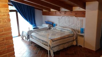 A bedroom with a bed, a nightstand, a dresser, and a window with curtains.