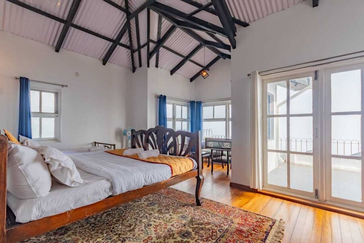 A bedroom with a wooden bed, a large window, and a balcony.