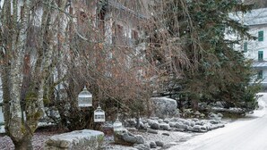 A snow-covered landscape with trees, rocks, and a building with green shutters. - Chalet 'Orserose I Masenin' with Mountain View, Shared Terrace and Wi-Fi (Forno di Zoldo BL)