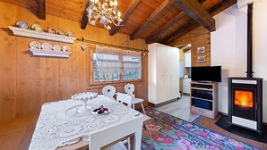 A wooden interior with a dining table, chairs, a chandelier, a fireplace, and a television. - Chalet 'Orserose I Masenin' with Mountain View, Shared Terrace and Wi-Fi (Forno di Zoldo BL)