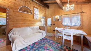A wooden interior with a sofa, a table, and a chandelier. - Chalet 'Orserose I Masenin' with Mountain View, Shared Terrace and Wi-Fi (Forno di Zoldo BL)