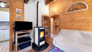 A wooden interior with a TV, a wood-burning stove, a sofa, and a decorative wall. - Chalet 'Orserose I Masenin' with Mountain View, Shared Terrace and Wi-Fi (Forno di Zoldo BL)