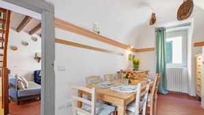 Un coin repas avec une table en bois, des chaises et une fenêtre avec un rideau.