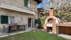 Un bâtiment en pierre doté d’un patio, de sièges en plein air et d’un four en briques.