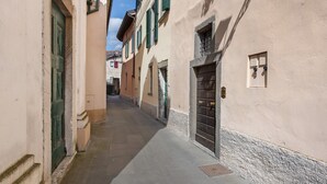 Une ruelle étroite, bordée de bâtiments des deux côtés, avec des portes et des fenêtres.