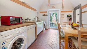 Une cuisine compacte équipée d’un lave-linge, d’un four à micro-ondes et d’un plan de travail en bois.