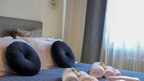 Una cama bien hecha con toallas enrolladas y un cojín decorativo.