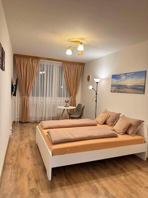 A bedroom with a bed, a chair, a small table, and a painting on the wall. - Apart for Rent Near Center (Prague)
