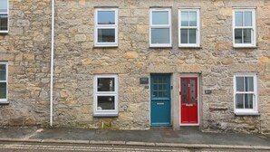 A stone building with multiple windows and doors, including a red door and a blue door. - Benjamin’s Bolthole, St Ives- Sleeps 4 - Outside Space – Dog-Friendly (St Ives)