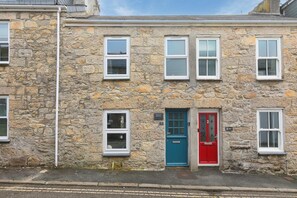 A stone building with multiple windows and doors, including a red door and a blue door. - Benjamin’s Bolthole, St Ives- Sleeps 4 - Outside Space – Dog-Friendly (St Ives)