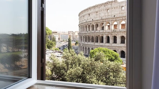 A view of the Colosseum with surrounding buildings and trees.