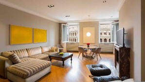 A modern living room with a sofa, coffee table, dining table with chairs, and a TV.